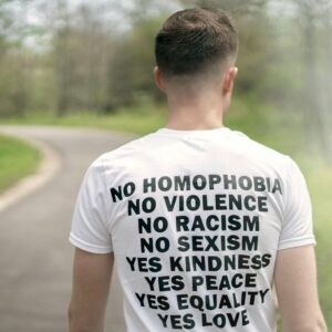 Man in a white T-shirt promoting equality and love during a peaceful walk outdoors.